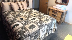 A bedroom with a bed, a wooden headboard, a dresser, and a mirror.