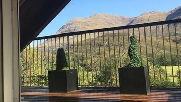 A balcony with a view of mountains, wooden flooring, and metal railings.