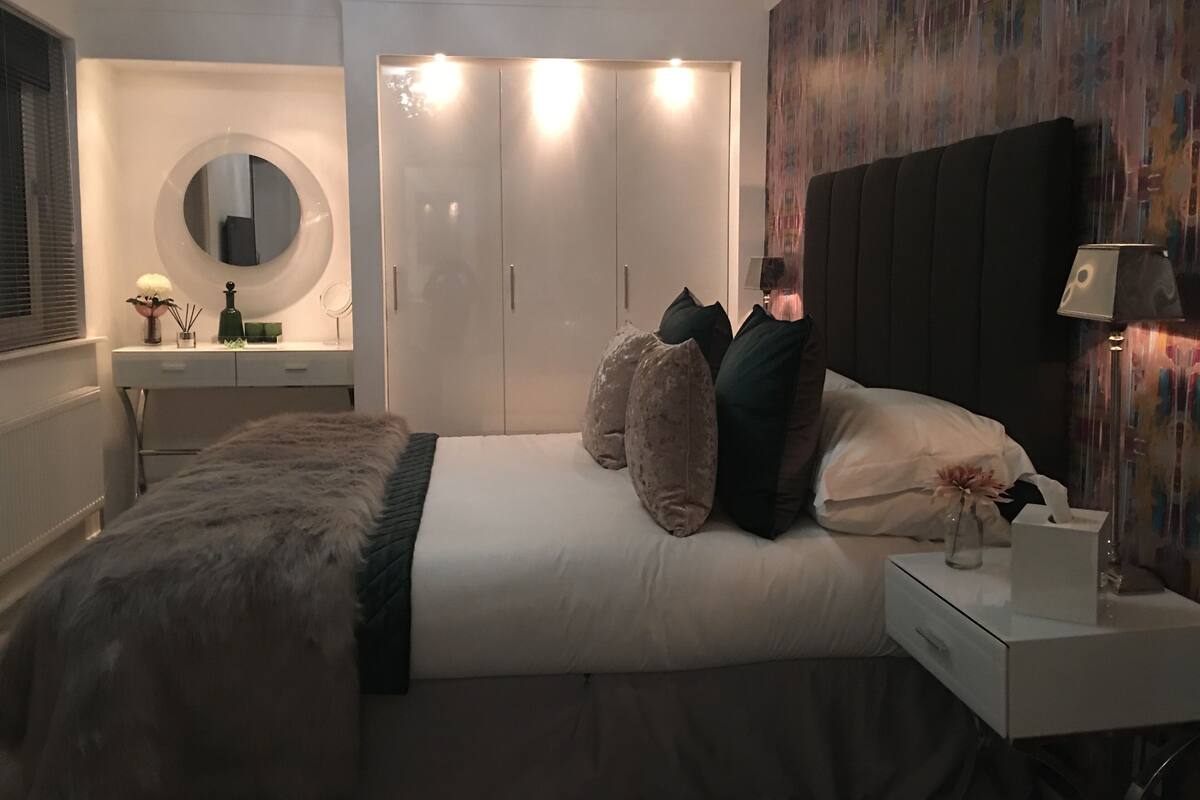 A bedroom with a bed, bedside table, lamp, and a wardrobe.