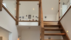 A modern interior with a wooden staircase, a wicker chair, and a glass railing. - Invercreran Lodge Luxury Bed & Breakfast (Appin)