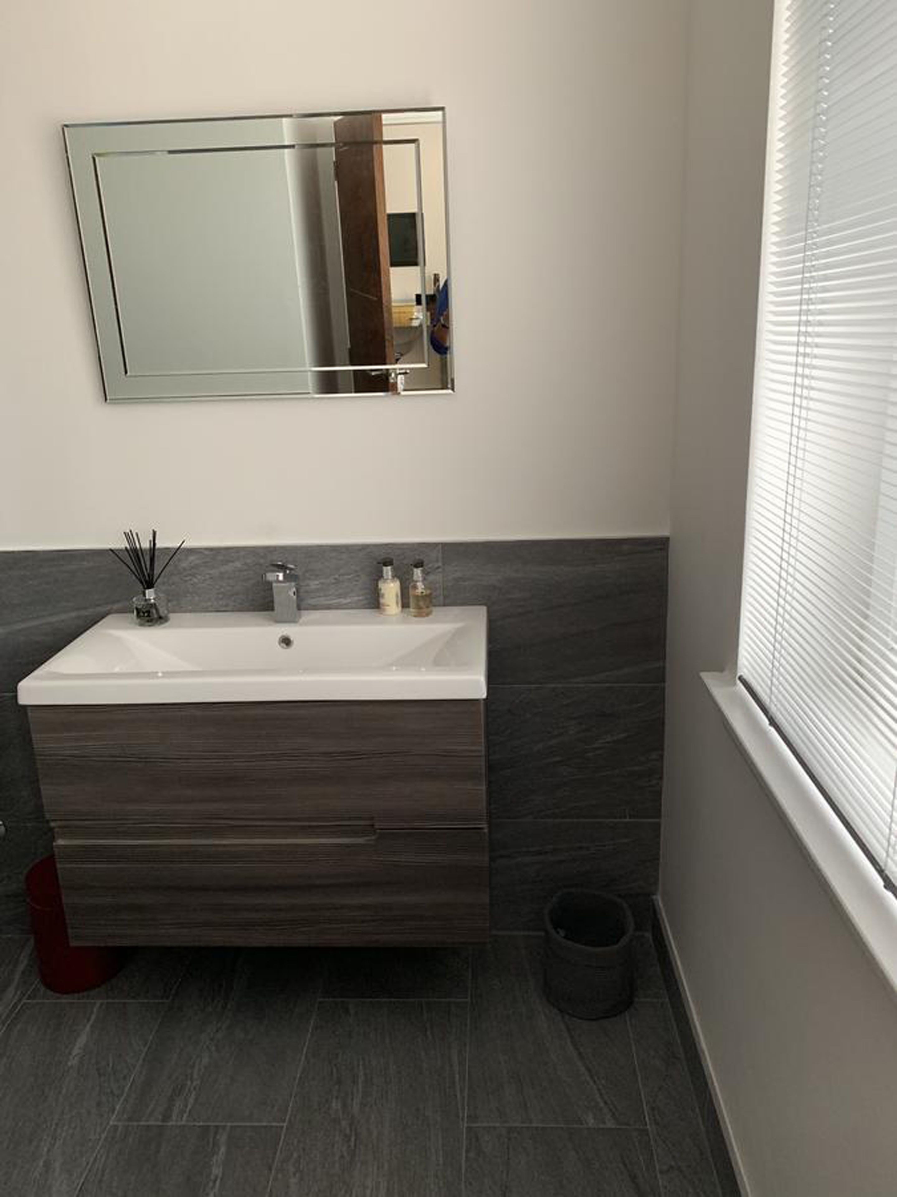 A bathroom with a rectangular sink, dark wood vanity, and a large mirror.