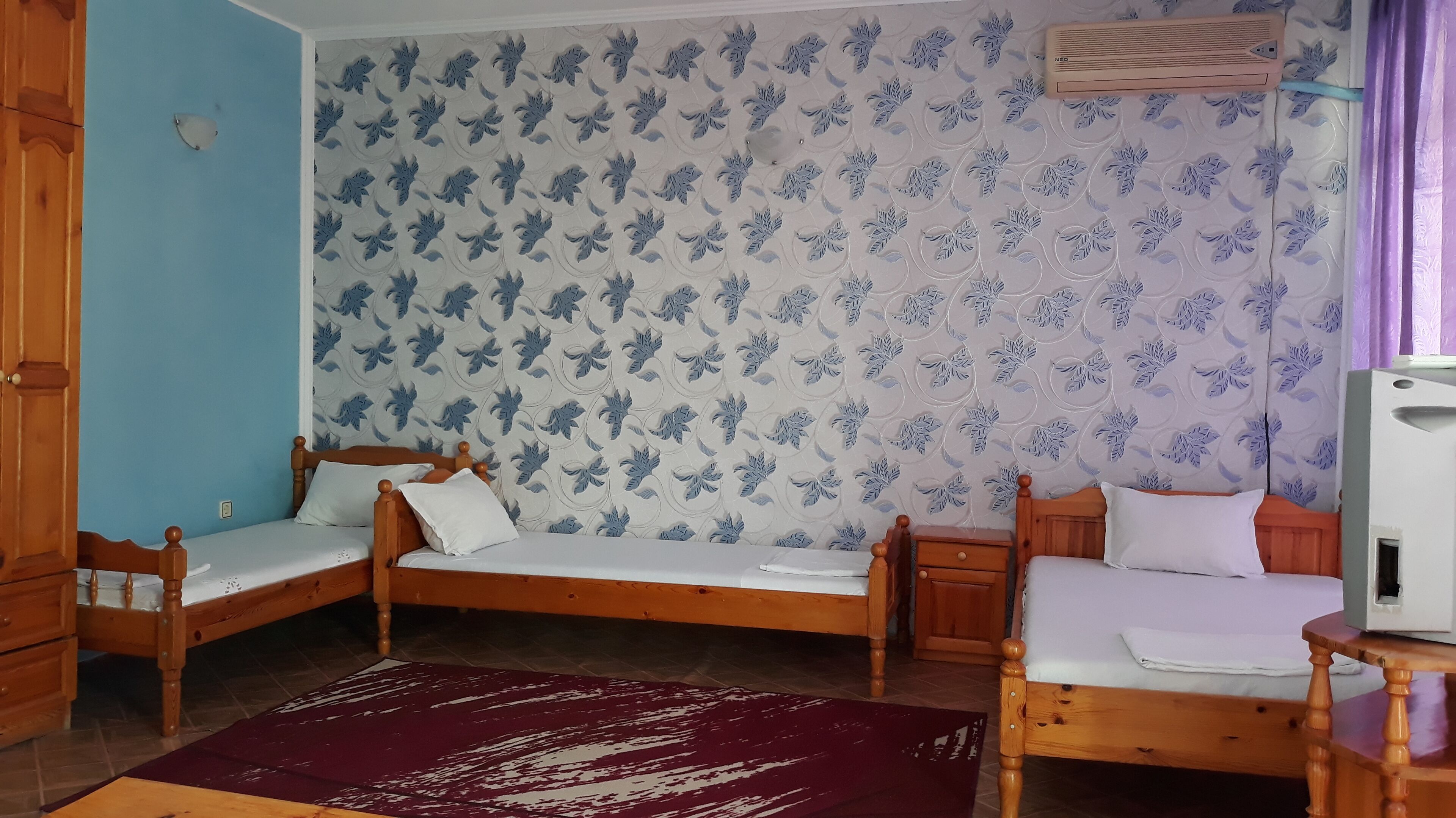 Una habitación con dos camas de madera, un armario de madera y una mesita de noche pequeña.