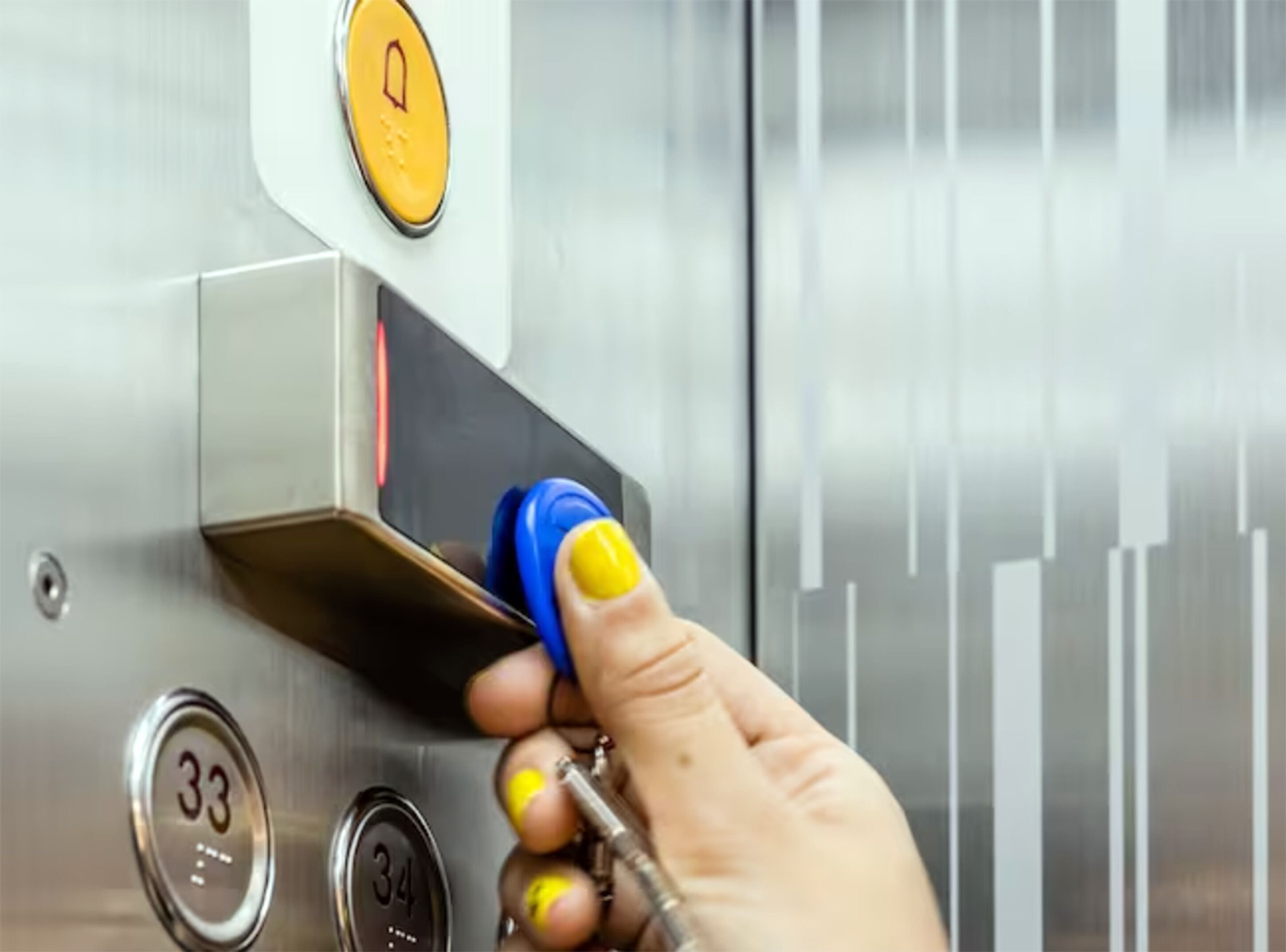 Een hand drukt op een knop van een bedieningspaneel in een lift.