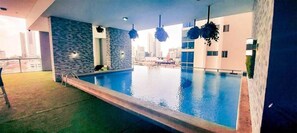 Une piscine intérieure avec un mur en pierre et des plantes suspendues.
