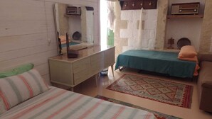 Ein kleines, gemütliches Zimmer mit einem Bett, einer Kommode, einem Spiegel und einem Radio.