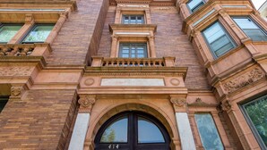 Un edificio con un ampio ingresso ad arco, un balcone con colonne e il numero "414" sulla porta.