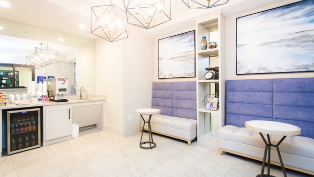 A modern hotel lobby with a reception desk, a seating area with a sofa and two small tables, and a large abstract painting on the wall. - Palace Inn Blue Federal Road (Houston)
