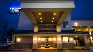 A hotel entrance with a prominent sign, a covered walkway, and a parking area. - Palace Inn Blue Federal Road (Houston)