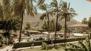 A resort with a swimming pool, palm trees, and a building with a red roof. - Solaya Kineret (Migdal)