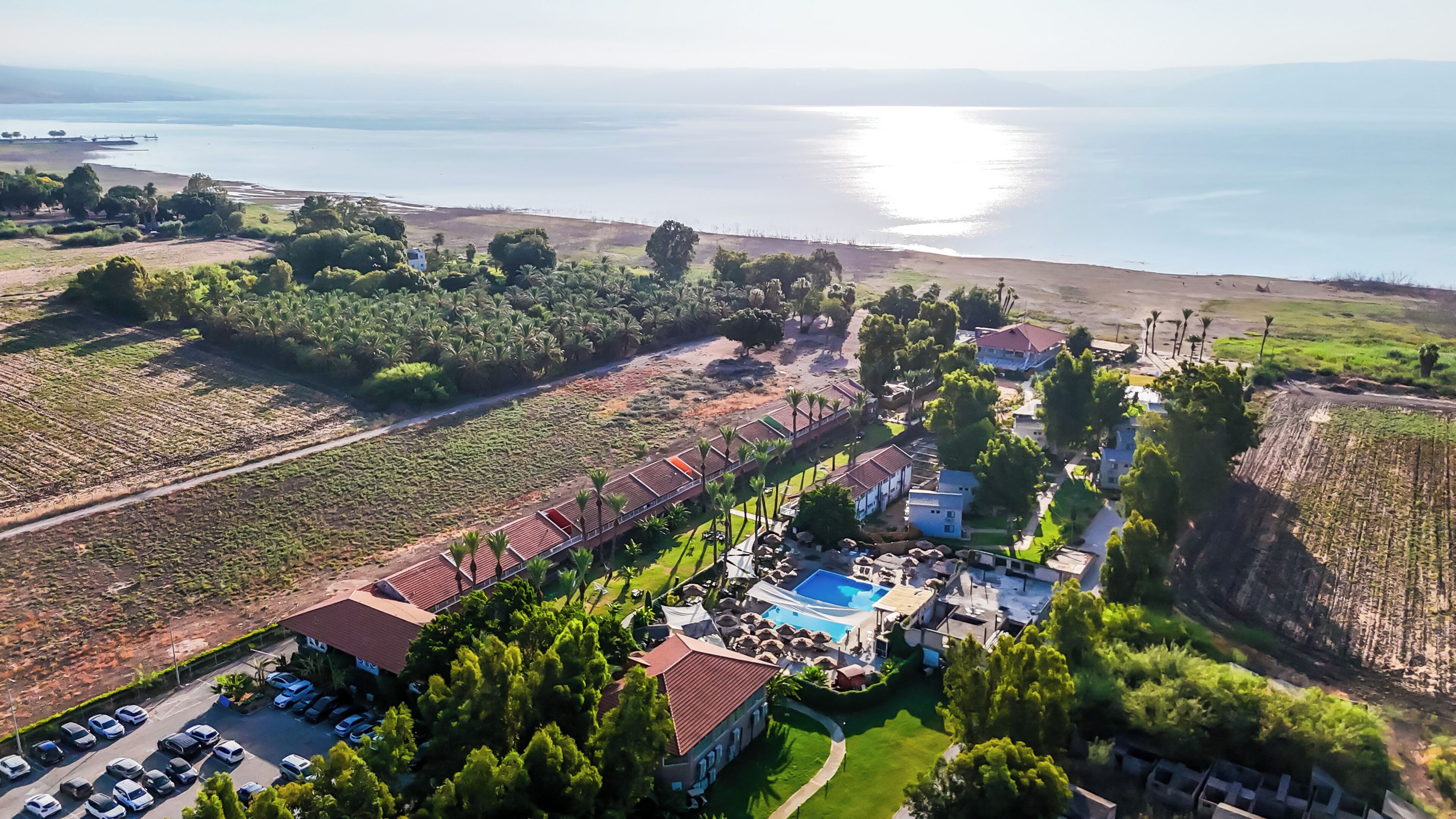 An aerial view of a resort with a swimming pool, multiple buildings, and a parking area.