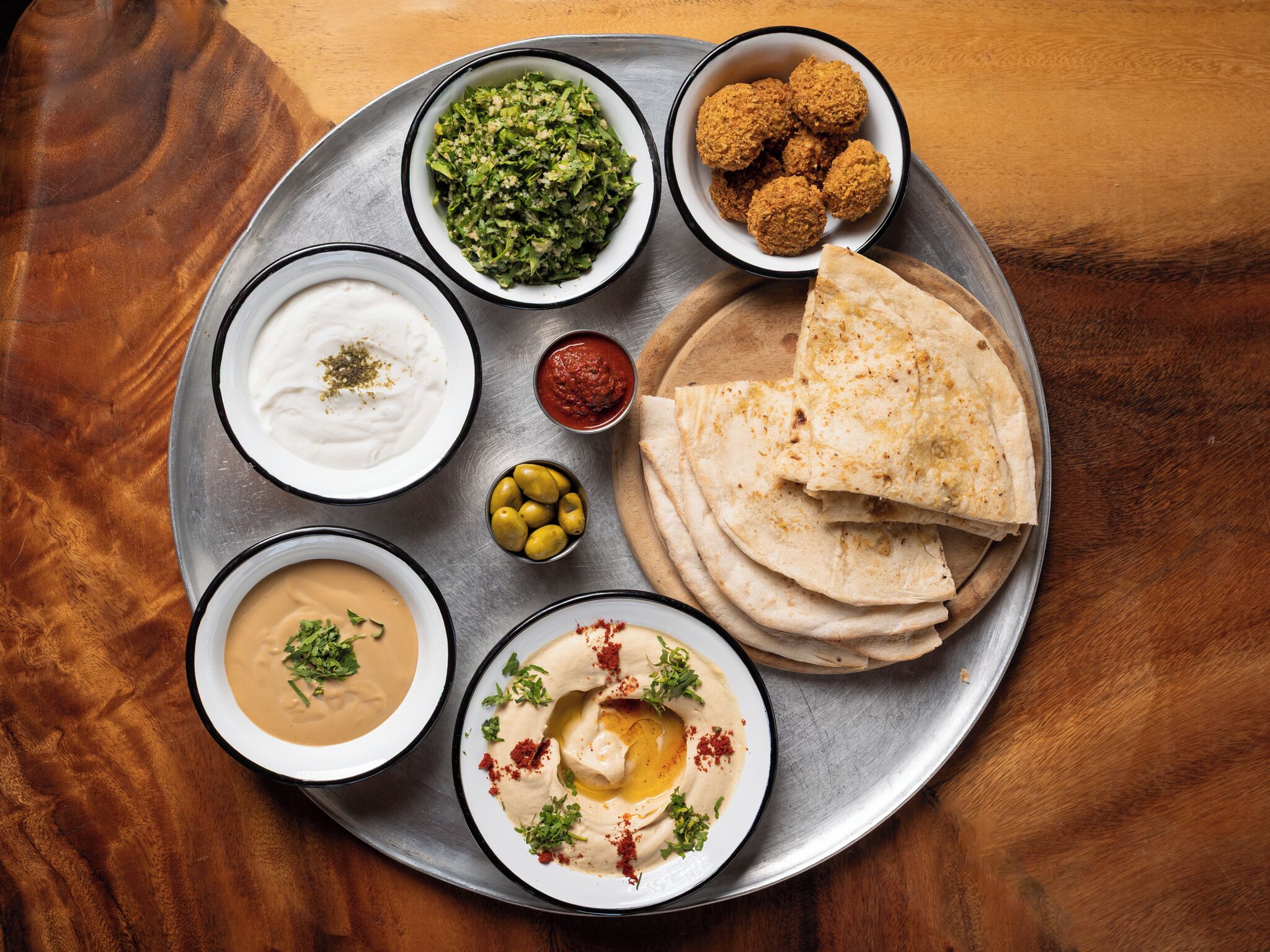Un plateau contenant divers plats, notamment du houmous, des falafels et du pain pita.