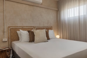 A neatly made bed with a headboard, a bedside table with a lamp, and a power outlet on the wall. - Solaya Kineret (Migdal)