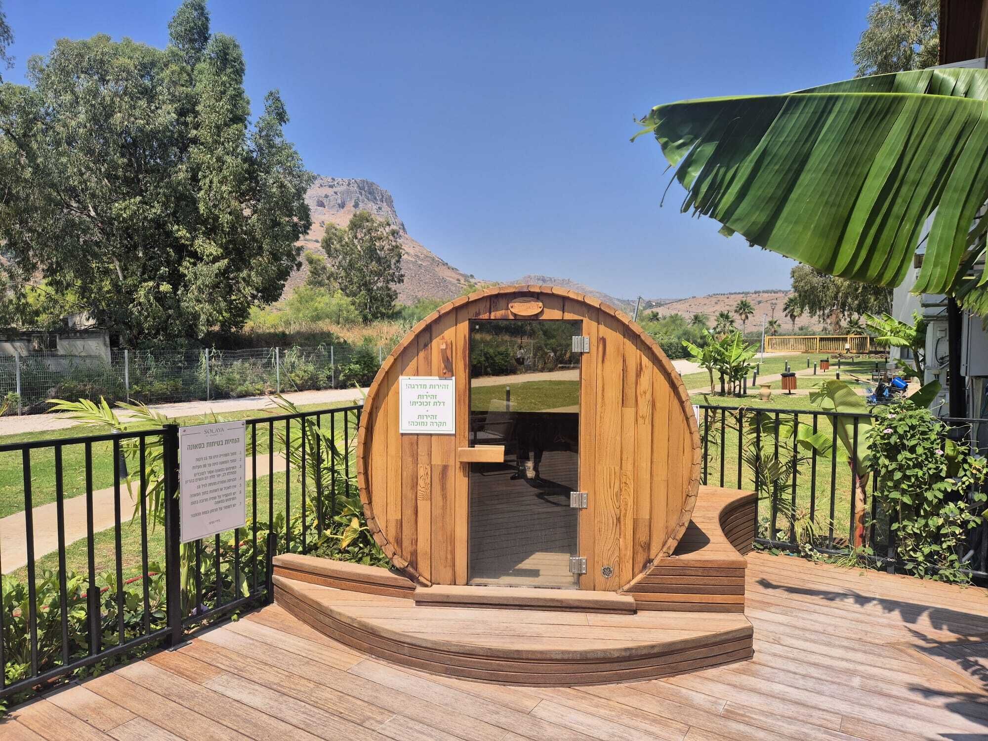 A wooden barrel-shaped structure with a sign, a wooden deck, and a view of a mountain and trees.