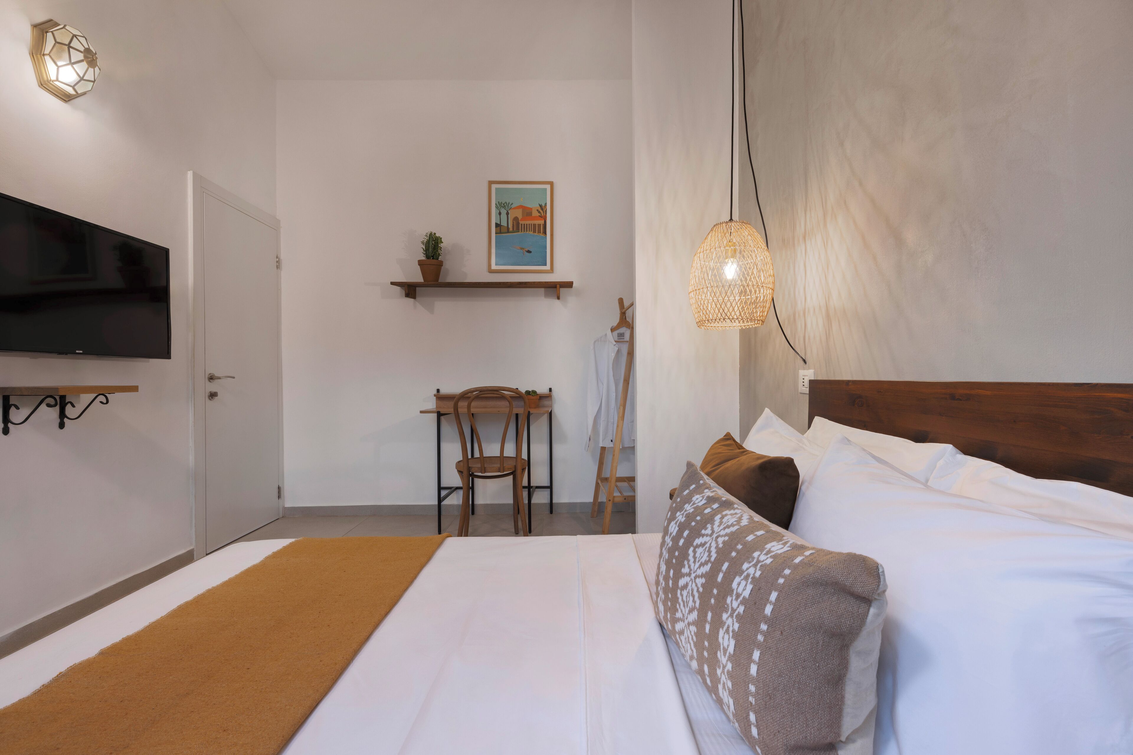 A bedroom with a bed, a TV, a desk, and a chair.