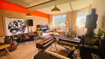 Una habitación con un piano, teclado y diversos instrumentos musicales.