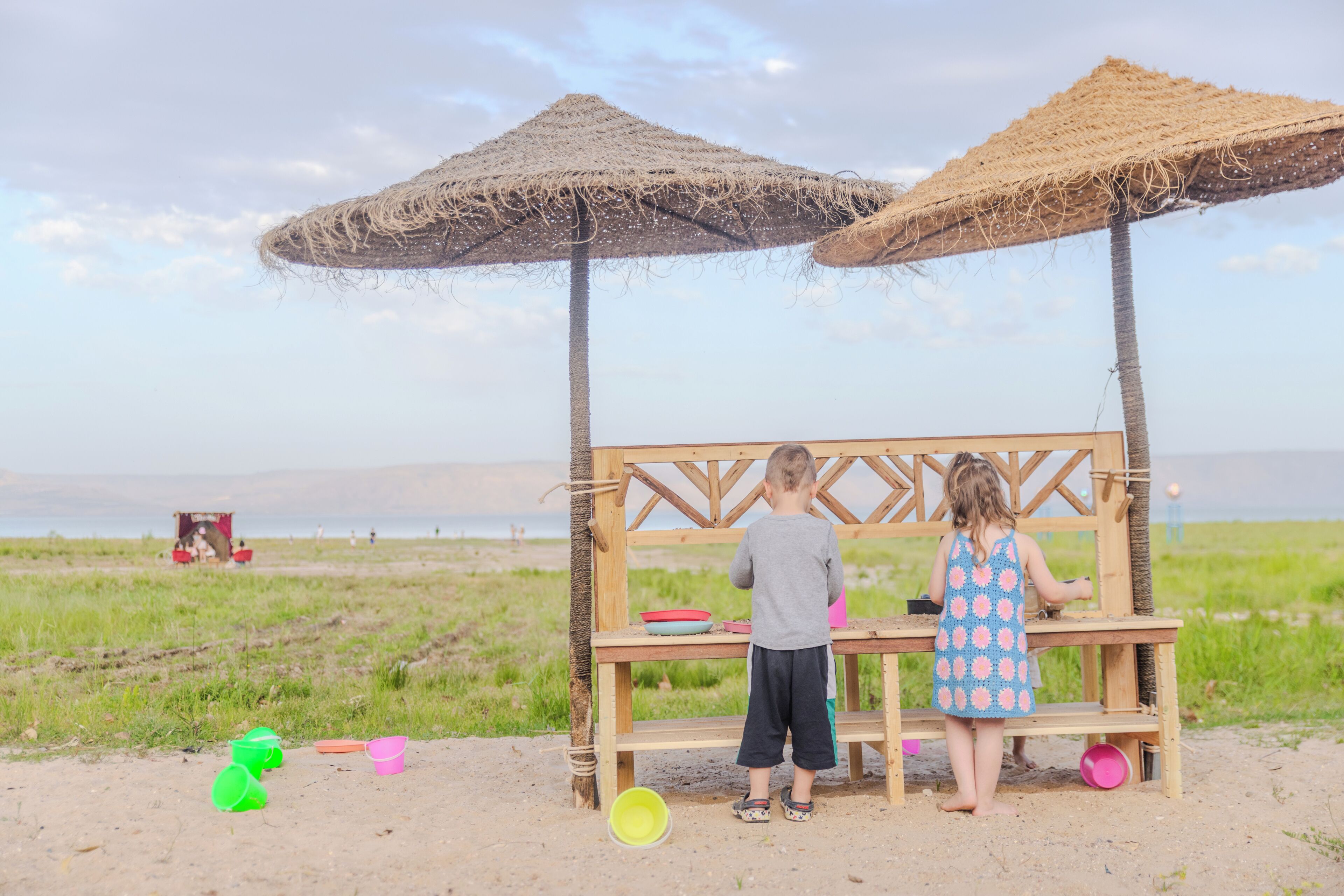 A beachside wooden structure with two thatched umbrellas, a table, and a view of the sea.