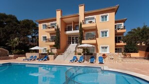 A multi-story hotel with a swimming pool, sun loungers, and a staircase leading to the entrance. - APT. ALMENDRO Grande, 2 bedrooms with air conditioning, balcony, pool, close to the beach 400 m, WIFI (Cala Sant Vicenç)