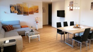 Ein modernes Wohnzimmer mit Sofa, Couchtisch und einem Essbereich mit Stühlen und Tisch.