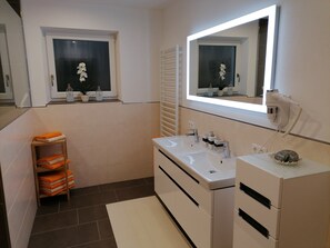 A modern bathroom with a white vanity, two sinks, a mirror, and a window with potted plants. - APPART DORNAUER in the beautiful Zillertal !! (Fügenberg)
