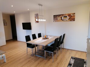 A modern dining area with a wooden table, black chairs, a ceiling light fixture, and a wall-mounted clock. - APPART DORNAUER in the beautiful Zillertal !! (Fügenberg)