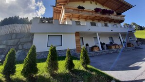 Ein zweistöckiges Gebäude mit Balkon, Steinmauer und gepflegtem Rasen.