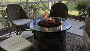 Un área de estar al aire libre con techado, sillas de mimbre y un hogar de piedra.