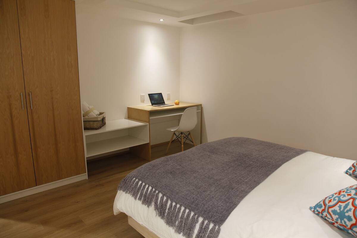 Un dormitorio con cama, escritorio y armario.