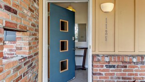 A blue door with three vents, a brick wall, and a beige wall with the number '12' above it.