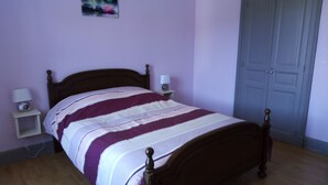 Un dormitorio con una cama de madera, una mesita de noche con una lámpara y una puerta.