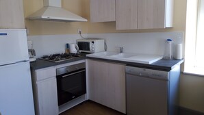 Cocina compacta con refrigerador, estufa, microondas, lavaplatos, horno y lavavajillas.