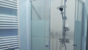 Ducha envuelta en vidrio con cabezal de ducha manual y opción de ducha a mano.