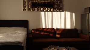 A room with a bed, a sofa, and a small table with remotes. - A perfect studio to stay - Studio Tony (Varna)