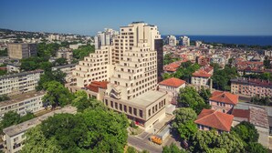 A high-rise building with multiple floors, surrounded by other buildings and greenery. - A perfect studio to stay - Studio Tony (Varna)