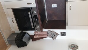 A kitchen with a built-in oven, a microwave, and a coffee machine. There is a trash bin and a clock on the wall. - A perfect studio to stay - Studio Tony (Varna)