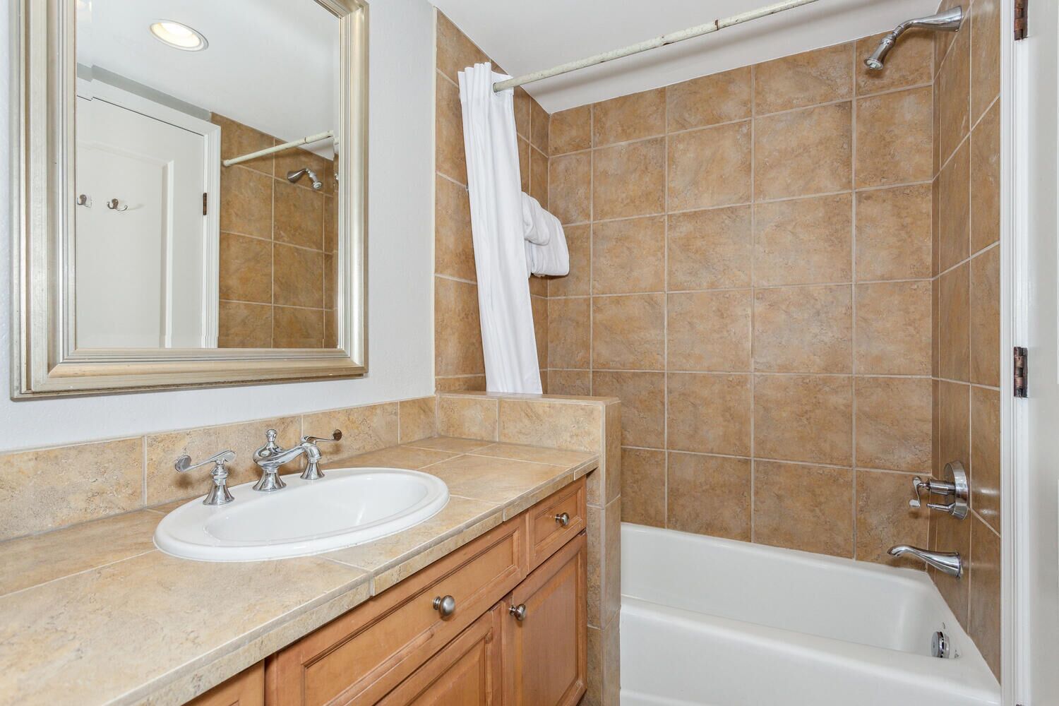A bathroom with a sink, mirror, shower, and bathtub.