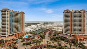 Een hoog hotel met meerdere verdiepingen, een centrale binnenplaats met een zwembad en uitzicht op het strand.