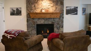 A living room with two brown leather sofas, a stone fireplace with a wooden mantel, and framed pictures on the walls. - 2000 sq foot exec apt./private vacation/quiet neighborhood close to ski resorts (Draper)
