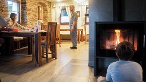 A cozy living room with a fireplace, wooden furniture, and a stone wall. - 120 m², holiday house, up to 19 people, 4 rooms with private bathrooms, sauna (Kovářská)