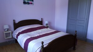 A bedroom with a wooden bed, a nightstand with a lamp, and a door. - Gite les Granites with balcony less than 100m from the lake (Gérardmer)