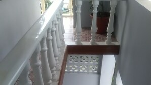 A staircase with white balustrades and blue steps, leading to a landing with a potted plant. - Tropicana Motel & Backpackers (Luganville)