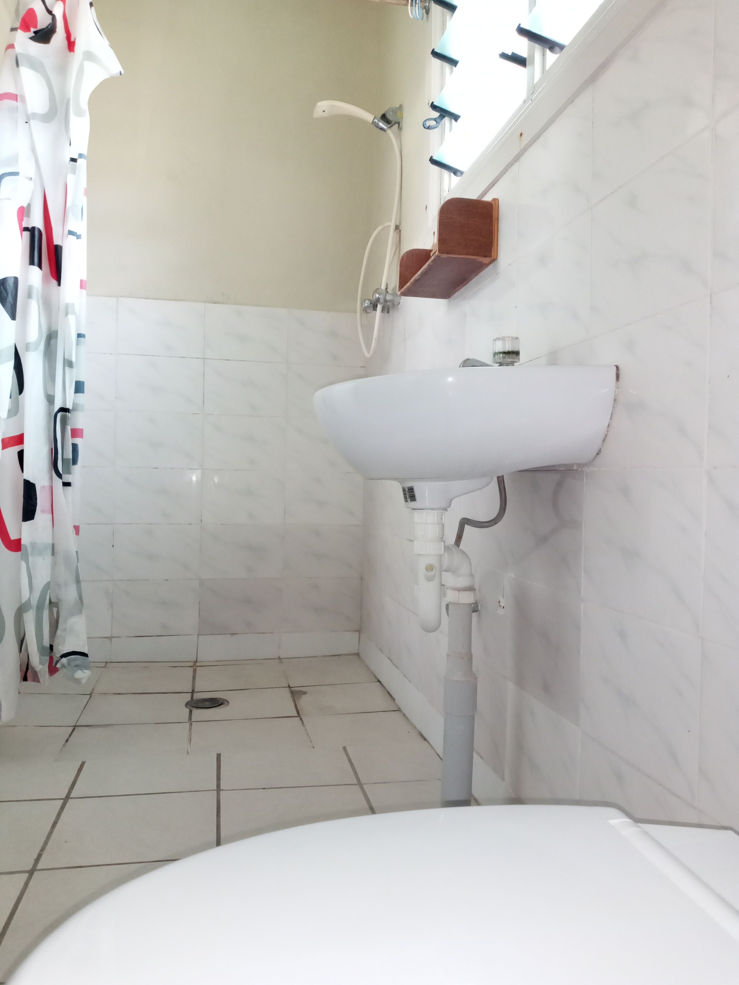 A bathroom with a white sink, a shower, and a tiled floor.