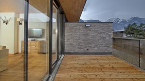 A modern interior with a stone wall, wooden floor, and a view of mountains. - luxurious apartment in the immediate vicinity of the valley station  (Neukirchen am Großvenediger)