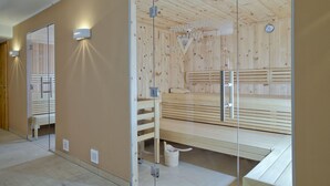 A sauna room with wooden walls and benches, a glass door, and a visible clock. - luxurious apartment in the immediate vicinity of the valley station  (Neukirchen am Großvenediger)
