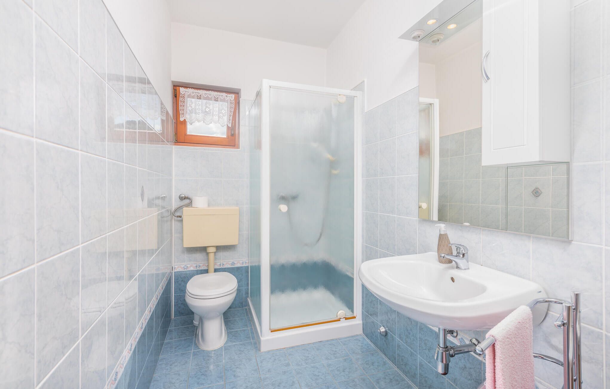Ein Badezimmer mit Toilette, einer Glasdusche, einem Waschbecken und einem Spiegel.