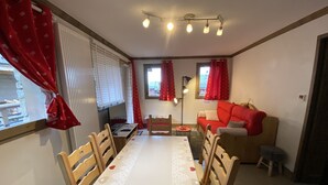 A dining area with a table set for four, a sofa, and a small stool.