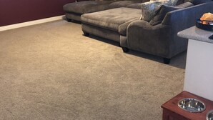 A living room with a grey sectional sofa, a small wooden table with a metal bowl, and a red accent wall. - Spacious House close to Laughlin, Lake and River - lots of parking. (Bullhead City)