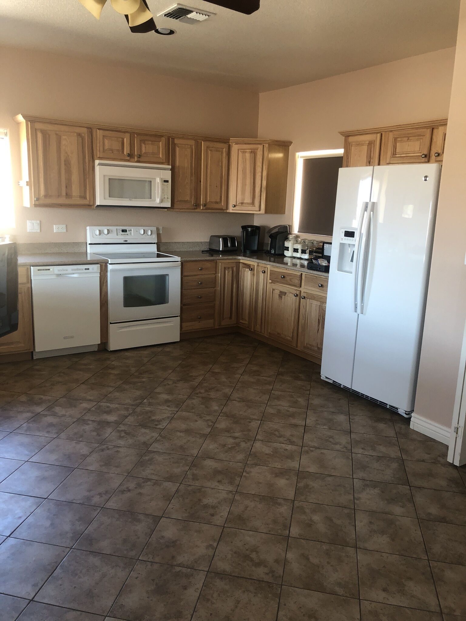 A kitchen with wooden cabinets, a white refrigerator, a microwave, an oven, and a toaster.