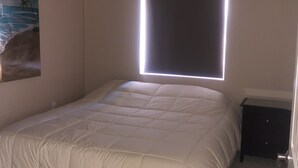 A bedroom with a bed, a ceiling fan, a nightstand, and a wall-mounted window. - Spacious House close to Laughlin, Lake and River - lots of parking. (Bullhead City)