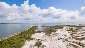 A coastal landscape with a beach, water, and vegetation. - Stunning Coastline Views at Portofino 2-1503! (Pensacola Beach)