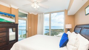 A hotel room with a bed, a television, a ceiling fan, and a view of the ocean. - Stunning Coastline Views at Portofino 2-1503! (Pensacola Beach)
